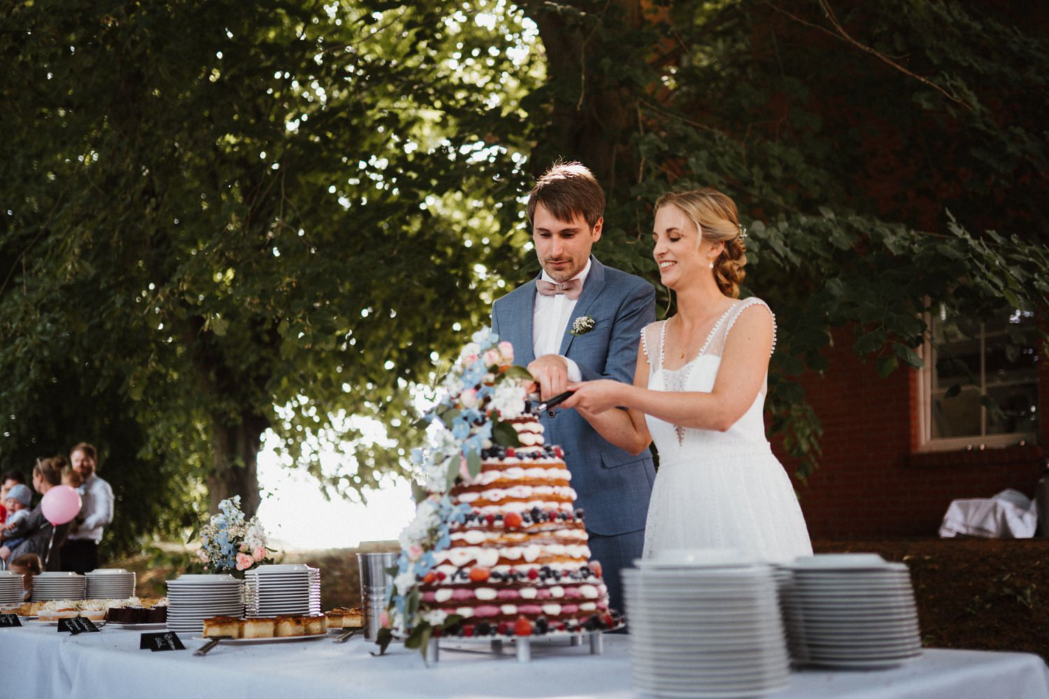Hochzeitstorte mit Ehepaar im Garten des Hotel Alte Schule Feldberger Seenlandschaft