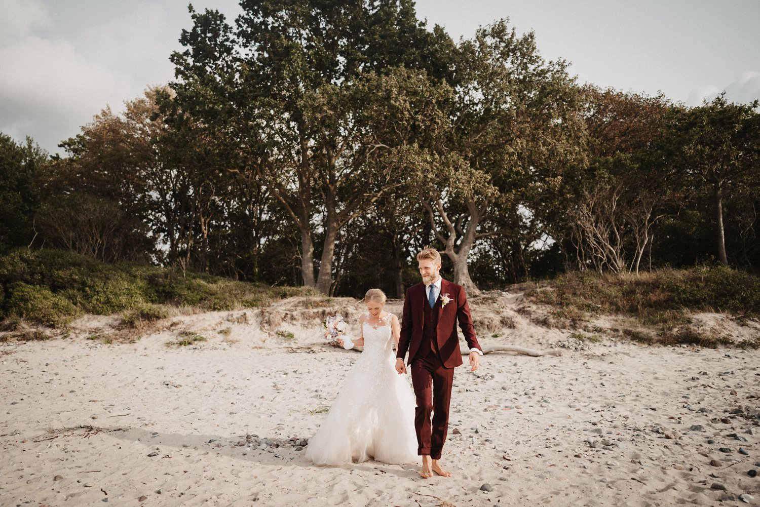 Braut und Bräutigem laufen barfuß am Strand der Ostsee an ihrem Hochzeits-Tag
